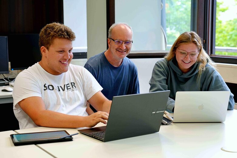 Ein Student, eine Studentin und ein Dozent befinden sich einem Seminar im Lehramtsstudium an der PHHD. Sie alle schauen motiviert und freundlich aus.