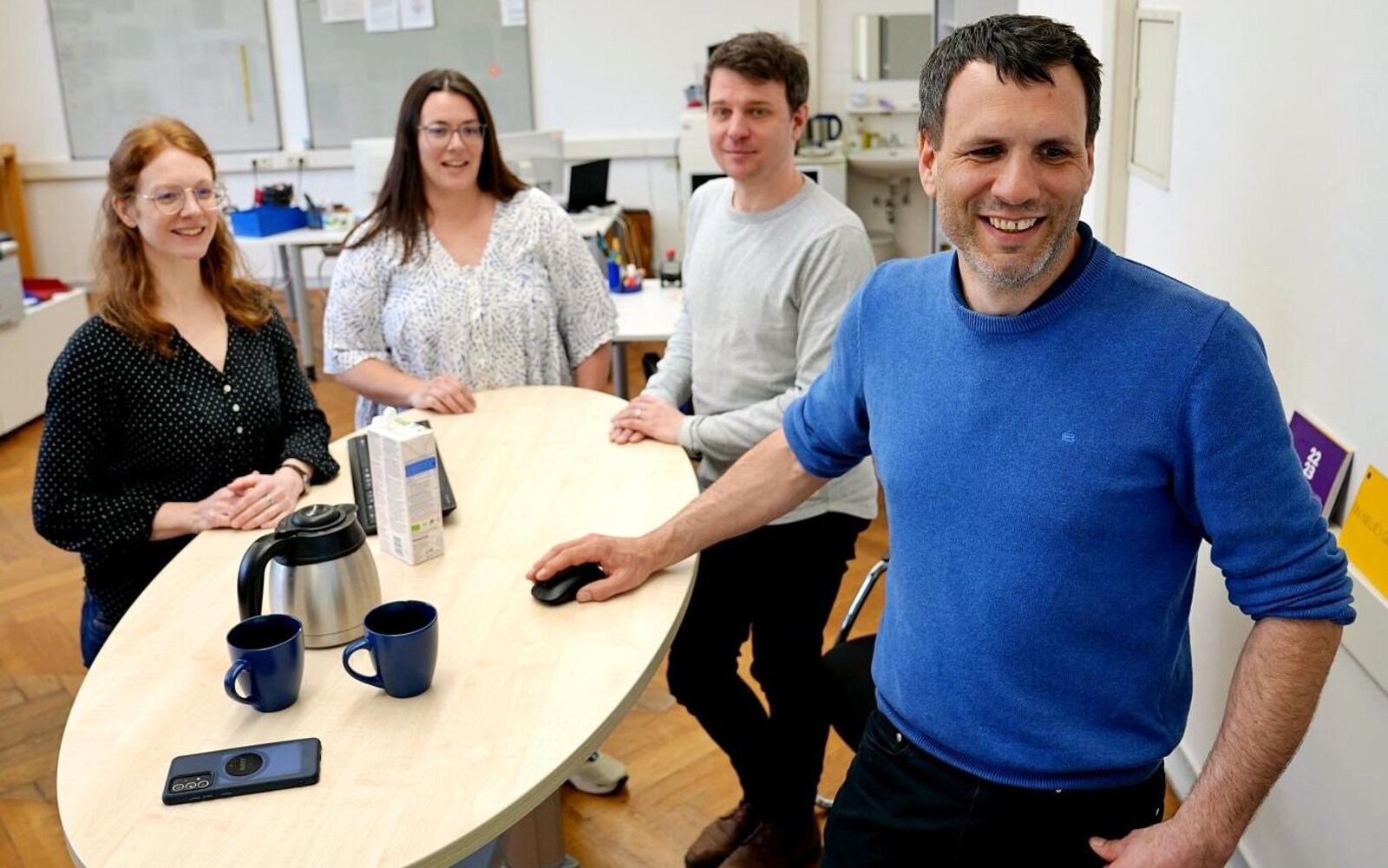 Eine Gruppe von Mitarbeiterinnen und Mitarbeitern der Pädagogischen Hochschule Heidelberg arbeiten gemeinsam an einem Stehtisch.