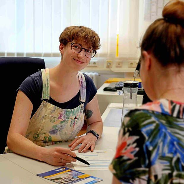 Mitarbeiterin des Studienbüros berät am Schreibtisch eine Studentin
