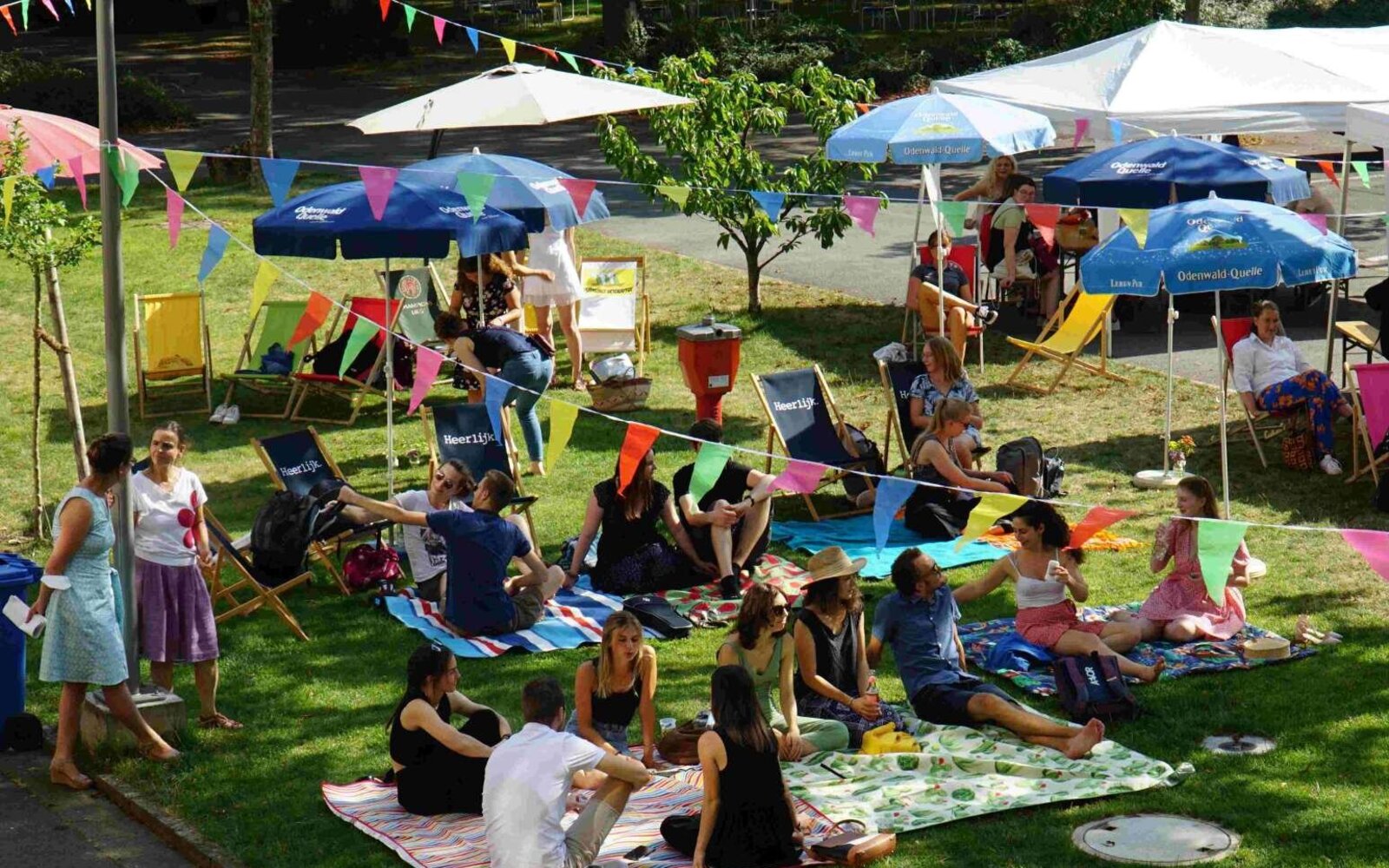 Foto von einer Veranstaltung im Hof des Altbaus der Pädagogischen Hochschule Heidelberg. Viele Menschen liegen auf dem Rasen auf Matten.